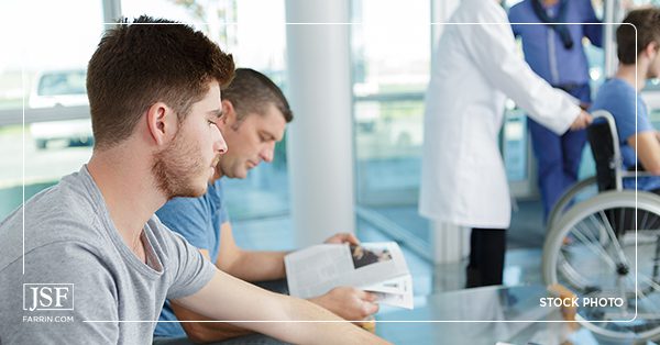 An injured worker waits for treatment and thinks about how he will receive Workers' Compensation pay